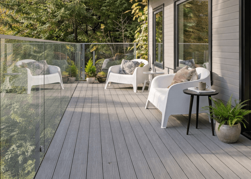 Grey MexyTech composite decking on a modern balcony with designer chairs and a glass balustrade