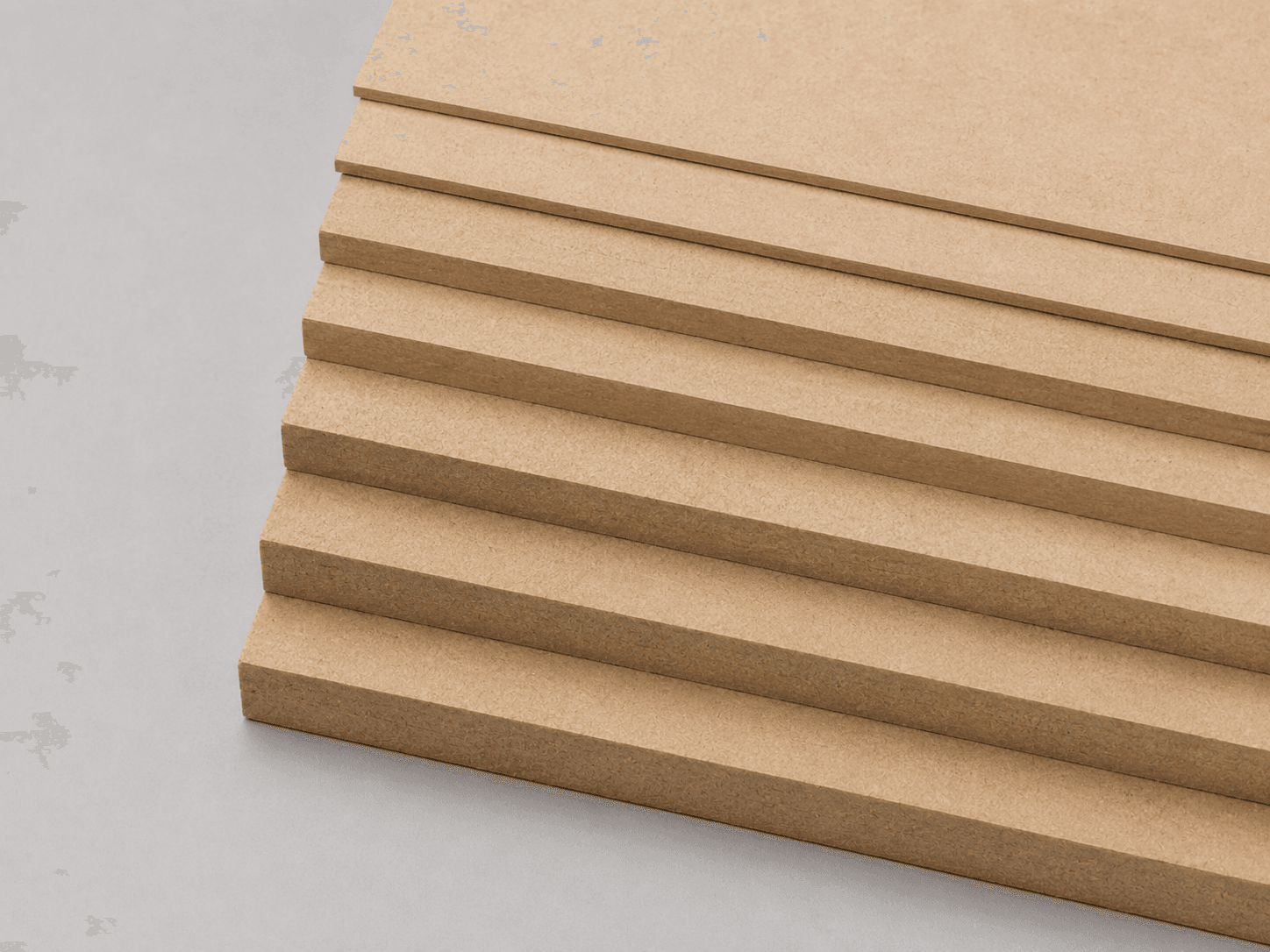 A fanned stack of medium-density fibreboard (MDF) sheets showing the smooth faces and dense edges